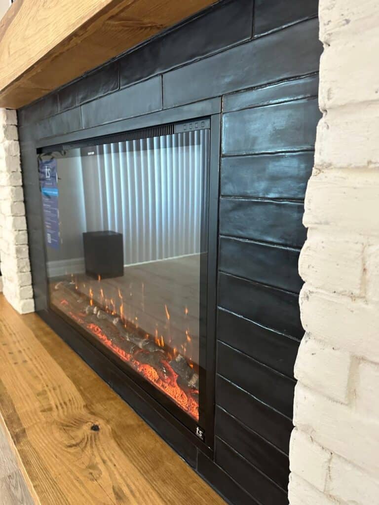 Chicago brick fireplace wall with black shiplap, electric fireplace and floating wood mantel
