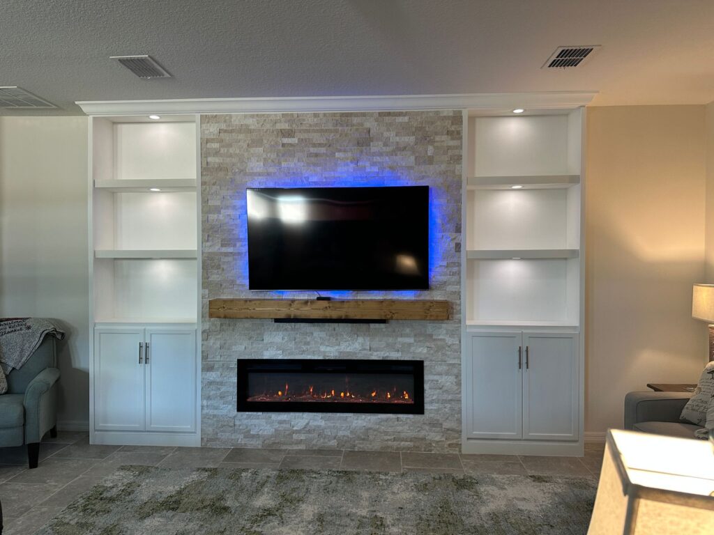 Custom stone fireplace wall with built in shelves cabinets and mounted TV in Florida living room