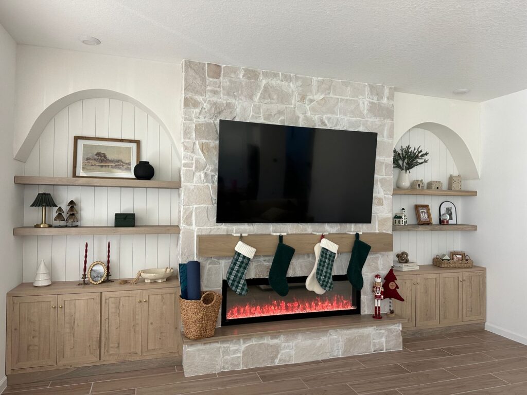 Custom stone fireplace wall with arched built in shelves and mounted TV in Florida home